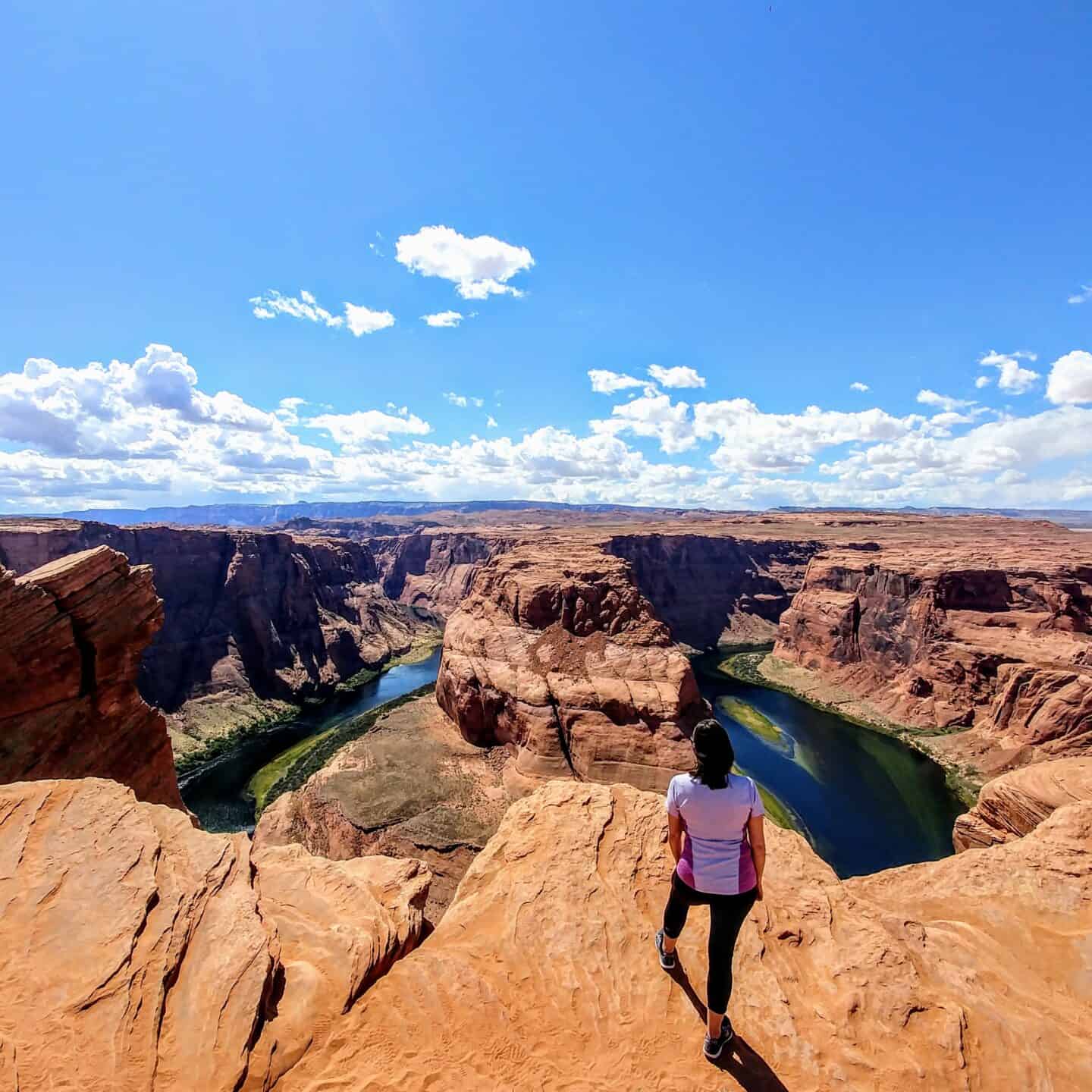 woman standing at ede of horsehoe bend page arizona day trip from scottsdale arizona
