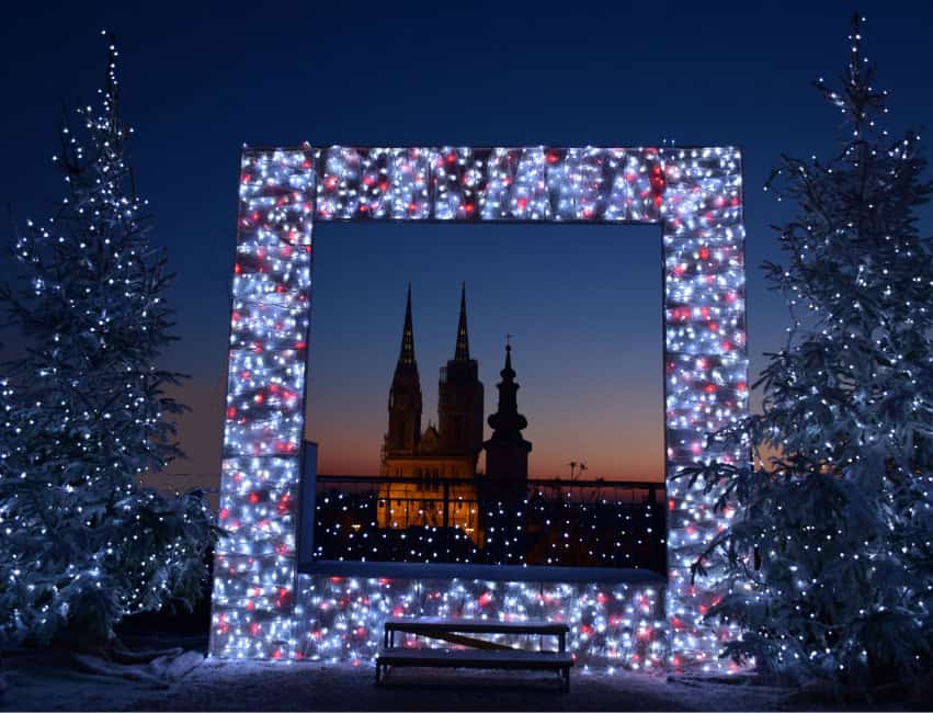 Christmas lights and wooden stalls at Zagreb’s Advent Market with a decorated tree and festive crowd.”