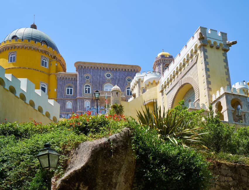 The fairytale-like Pena Palace with vivid colors, turrets, and panoramic views of the Sintra mountains and forests.