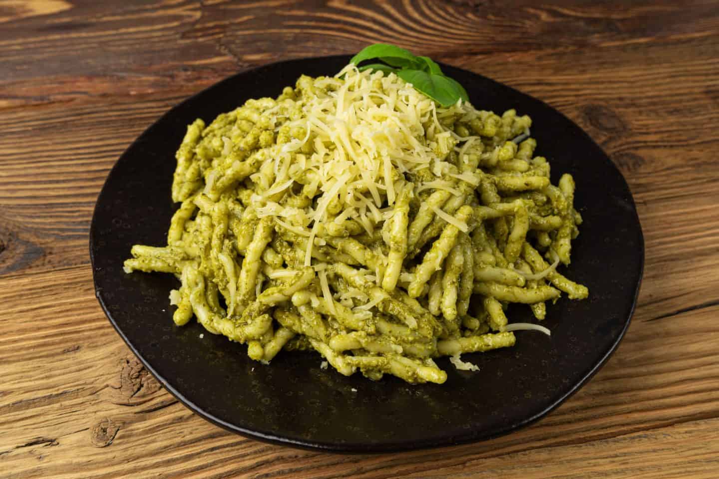 trofie al pesto Trofie alla Genovese plated on black plate with cheese