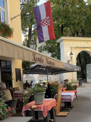 Croatian flag outside a restaurant in a cozy outdoor dining area.