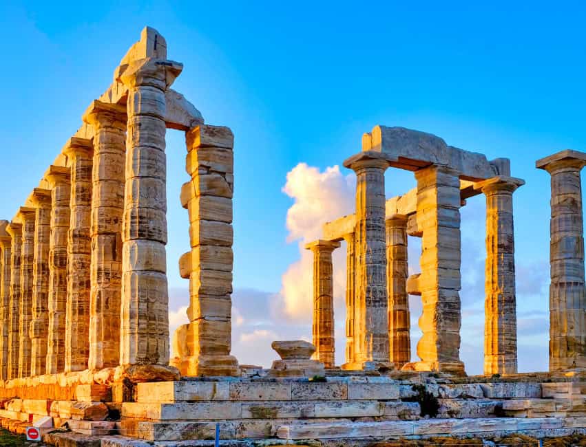 Temple of Poseidon on Cape Sounion cliff at sunset overlooking the Aegean Sea.
