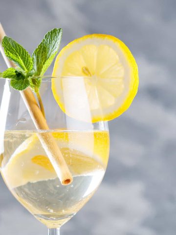 Limoncello spritz cocktail Bright yellow limoncello spritz served in a stemmed wine glass with lemon slices, prosecco bubbles, and fresh mint. #limoncellospritz #spritz