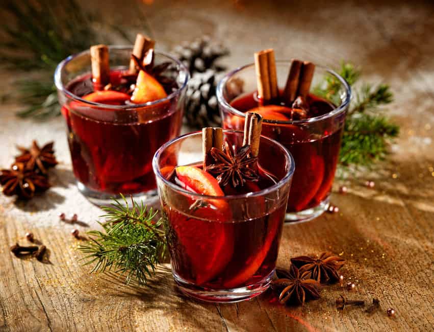 christmas cocktails table of glasses with mulled wine with orange slices, cinnamon sticks and christmas decor