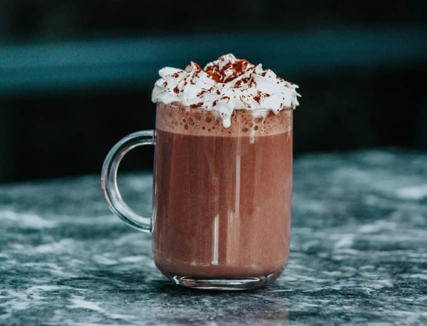 christmas drinks hot chocolate in clear glass with whipped cream and chocolate shavings