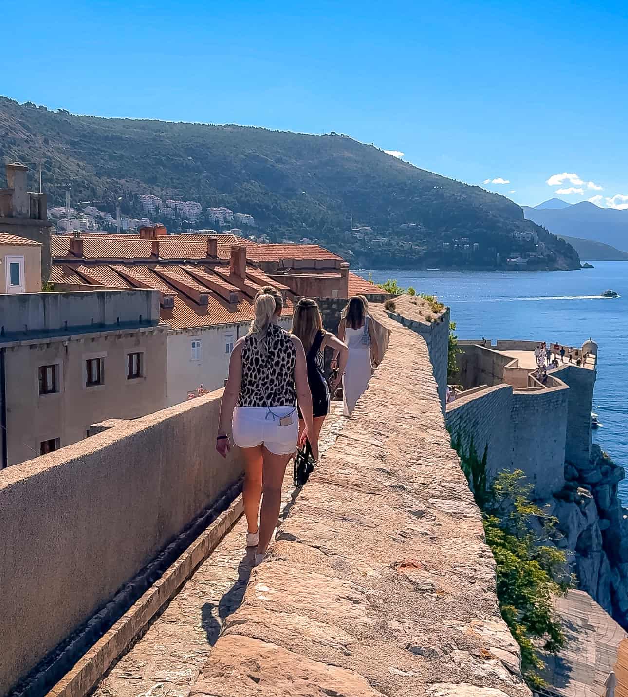 people walking on dubrovnik city walls with a view of the sea where to stay in dubrovnik 10 days in croatia itinerary