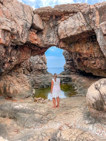 Sea caves on Lokrum Island Croatia with turquoise water splashing against limestone cliffs.