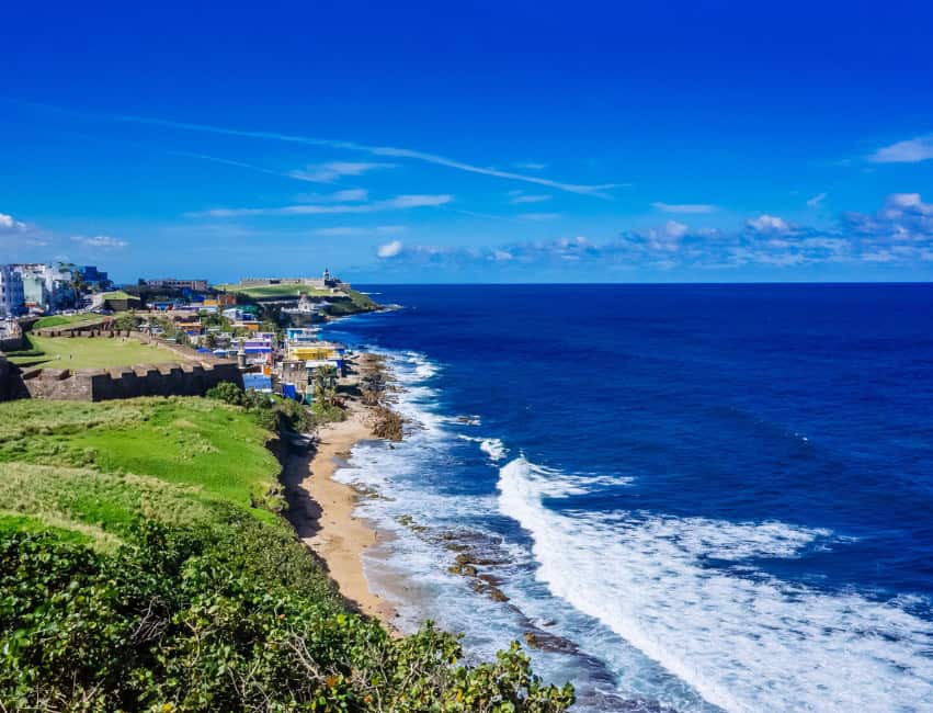 rocky shoreline with view of green hills and beach in puerto rico best caribbean islands to visit