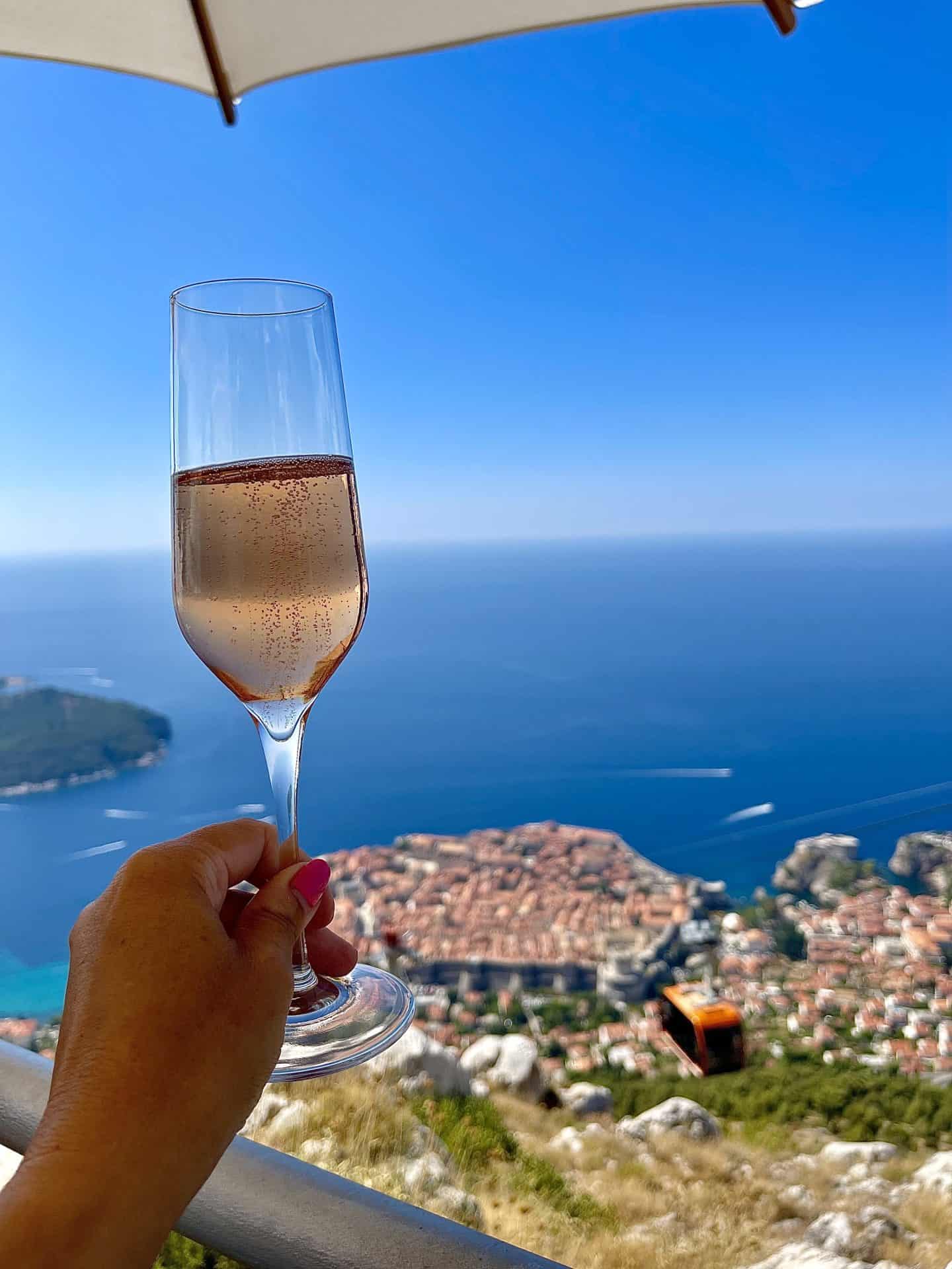 glass of champagne with view of dubrovnik cable car and dubrovnik old town