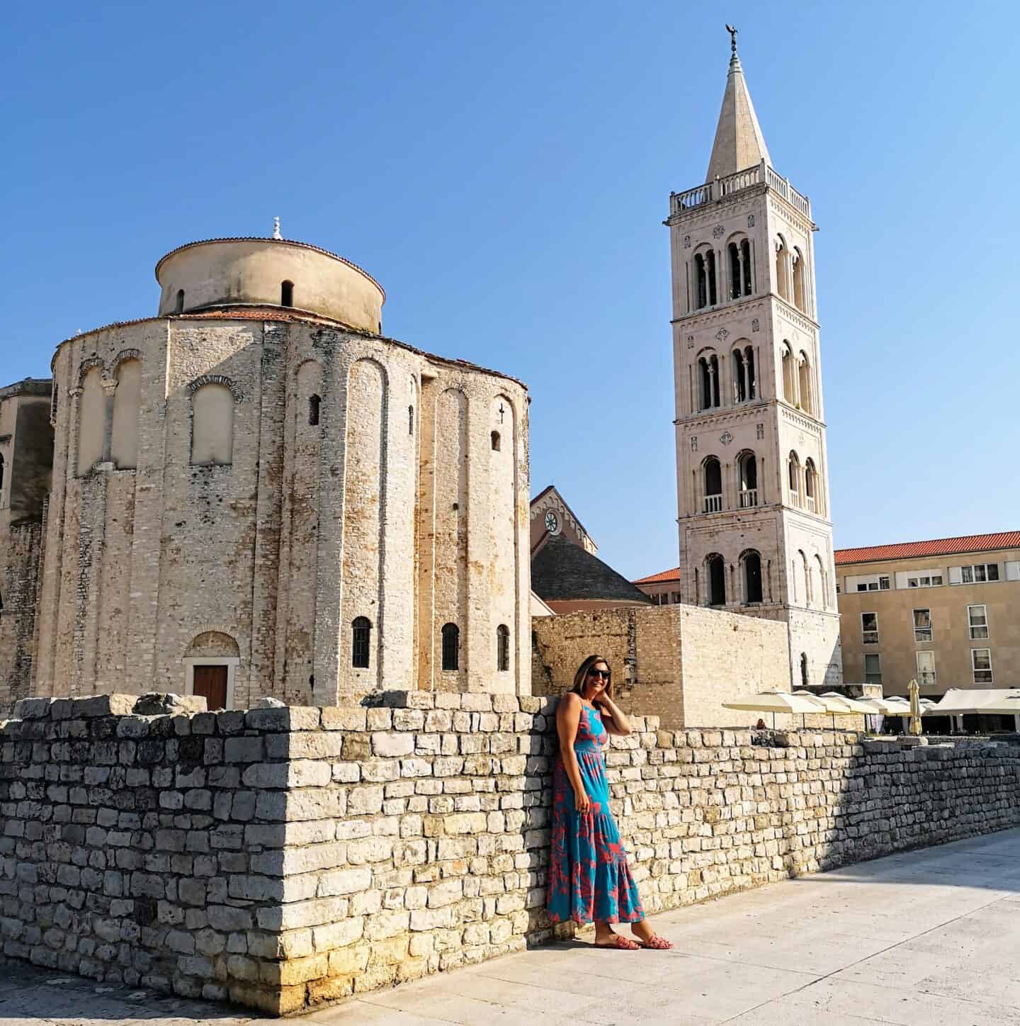woman in blue dress standing in front of Zadar Croatia architecture