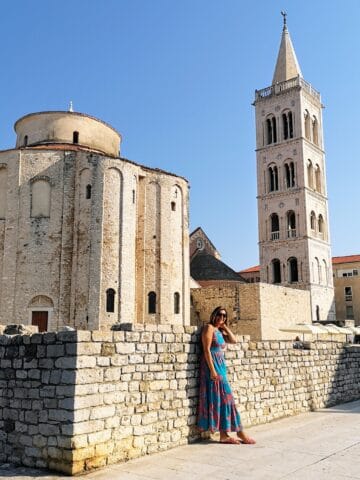 woman in blue dress standing in front of Zadar Croatia architecture