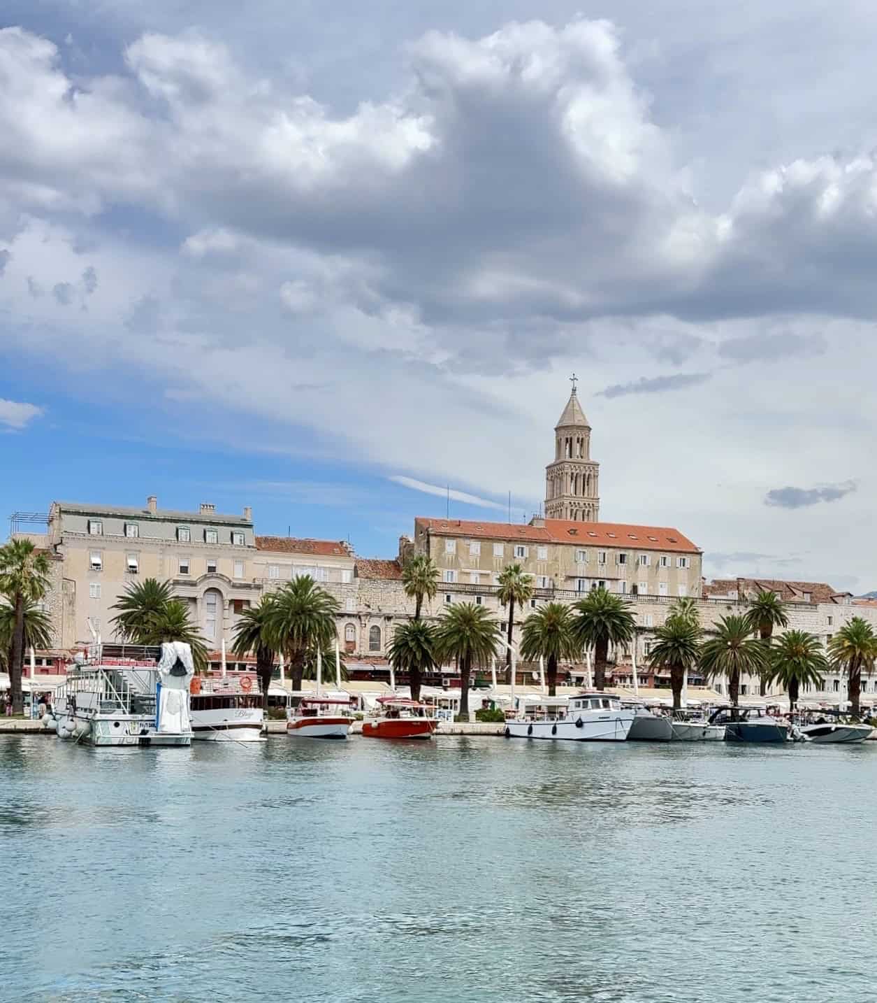 Beautiful Croatian harbor with historic buildings and palm trees.