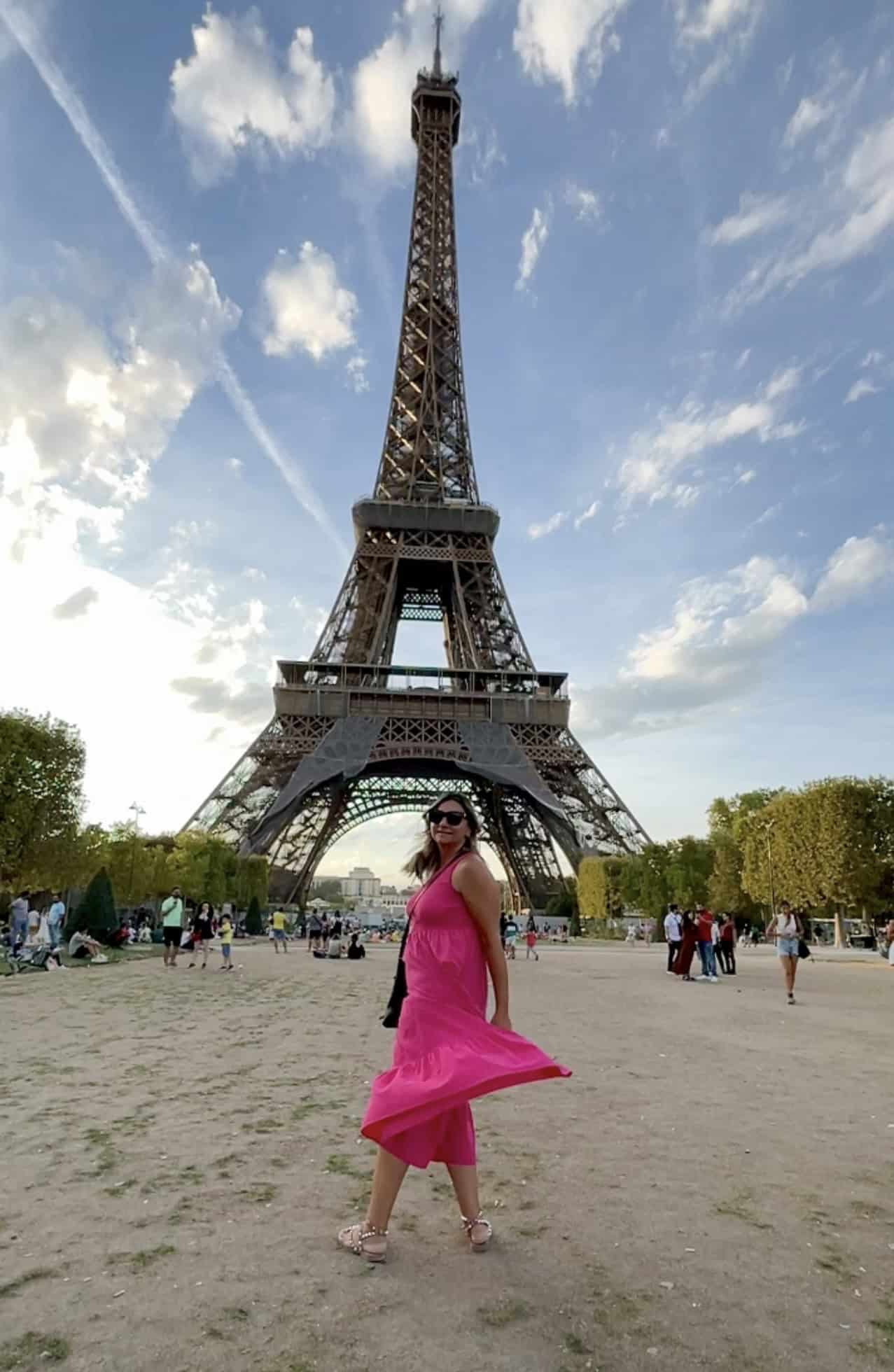 woman in pink dress twirling in front of the Eiffel tower in Paris