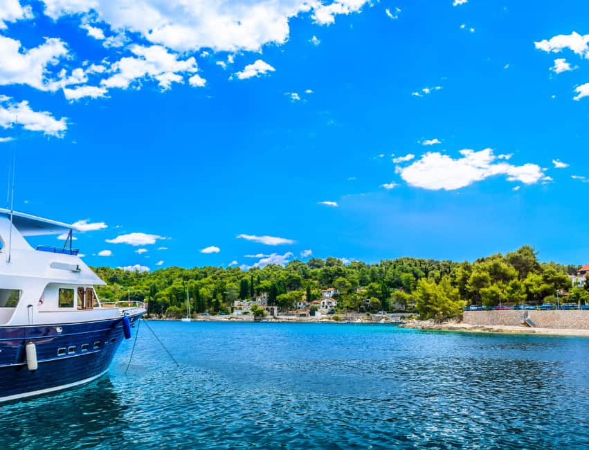 Harbor view of a yacht on calm waters with lush green hills in the background in Solta Croatia